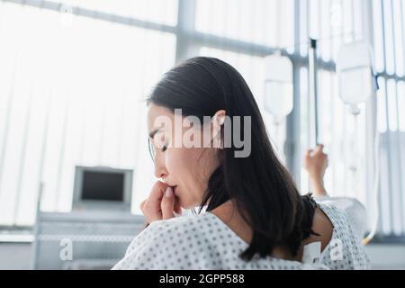 donna malata con occhi chiusi che sente dolore durante la terapia in ospedale Foto Stock