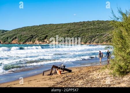 I surfisti che portano le loro tavole da surf su una spiaggia sabbiosa, nel golfo di Baratti, Piombino, provincia di Livorno, Italia. Foto Stock