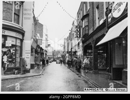 Queen Street, Ramsgate, Thanet, Kent, c1945-c1965. Una vista sulla strada di Queen Street, vista da est vicino all'incrocio con York Street, e guardando a ovest con una vista parziale di 51 Queen Street sullo sfondo. 51 Queen Street è sullo sfondo della fotografia, e può essere situato dalla faccia di orologio rotondo sostenuto da una grande staffa. L'edificio è l'ex sede di un mercante di vino, costruito intorno al 1898 e progettato da WJ Jennings di Canterbury. E' stato costruito in stile Vittoriano-Tudor. La facciata anteriore ha un ingresso centrale fiancheggiato da colonne di granito e una breve torre circolare sul Foto Stock