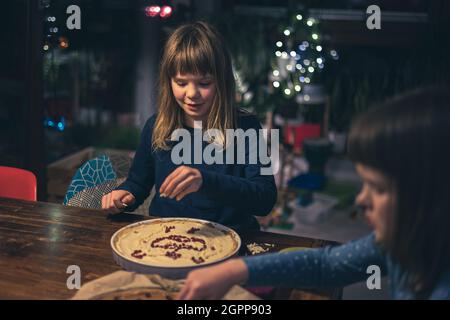 Bambini che decorano mazurek (torta di Pasqua polacca) a casa Foto Stock