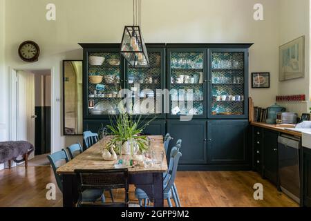 Credenze teal da cucina con lampada a sospensione sopra il tavolo in ex scuola Somerset 19 ° secolo. Foto Stock