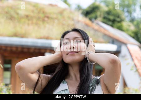 Germania, Friburgo, sorridente giovane donna con la testa nelle mani Foto Stock