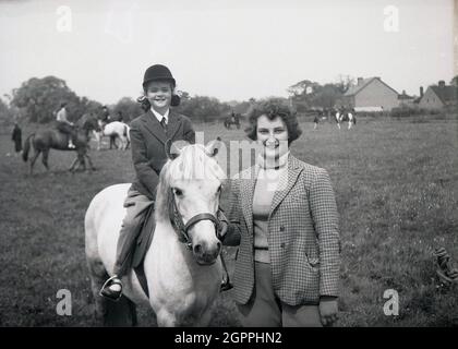 Anni '50, storica, una madre orgogliosa accanto a sua figlia seduta sul suo cavallo fuori ad una competizione equestre di evocazione, Sussex, Inghilterra, Regno Unito. Foto Stock