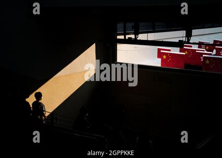 Hong Kong, Cina. 30 settembre 2021. Una donna guarda le bandiere cinesi e di Hong Kong dall'interno dell'edificio in vista della Giornata Nazionale della Repubblica popolare Cinese il 1 ottobre. (Credit Image: © Keith Tsuji/ZUMA Press Wire) Foto Stock