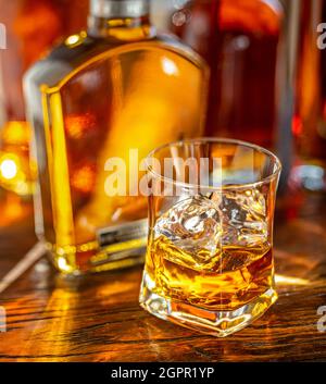Whiskey decanter e bicchiere di whiskey sul banco bar in legno da vicino. Foto Stock