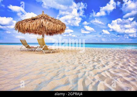 Ombrellone e sdraio in paglia su una costa di sabbia ideale Foto Stock