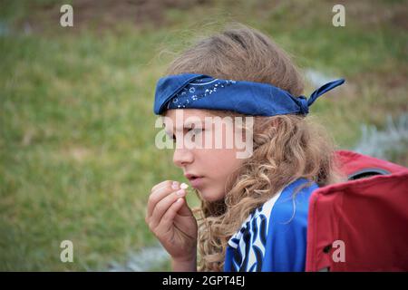 Preoccupato giocatore di calcio di 11 anni con la fascia blu della testa e lo spazio di testo o di copia che guarda la sua squadra perdere Foto Stock