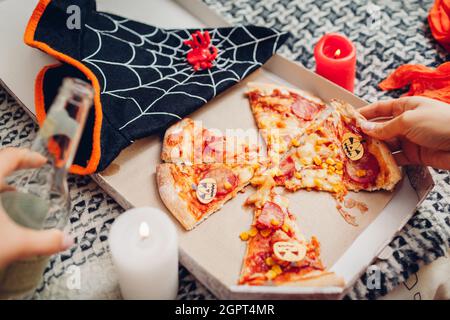 Pizza di Halloween con pumpkins di carta jack-o-lanterna. Festa di festa con candele e costumi. Halloween cibo con bevanda in bottiglia Foto Stock