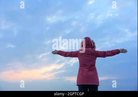 La signora con le braccia tese verso il mare Foto Stock