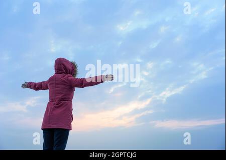 La signora con le braccia tese verso il mare Foto Stock