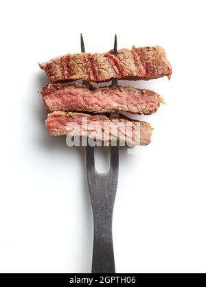 Fettine di bistecca di manzo su forchetta di carne isolate su sfondo bianco; vista dall'alto Foto Stock