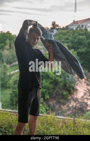 Ritratto del giovane bel caucasico con tatuaggio a braccio pieno in casual indossando, camminando e guardando la macchina fotografica con spazio copia. Indossa una giacca in denim Foto Stock