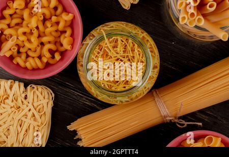 vista dall'alto di diversi tipi di macaroni come bucatini cavatappi spaghetti vermicelli tagliatelle e altri su sfondo ligneo Foto Stock