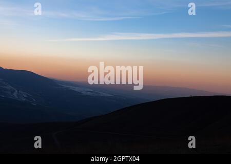 Prima del tramonto, sulla cima della montagna si erge un cavallo solato. I maestosi Monti Tian Shan Foto Stock