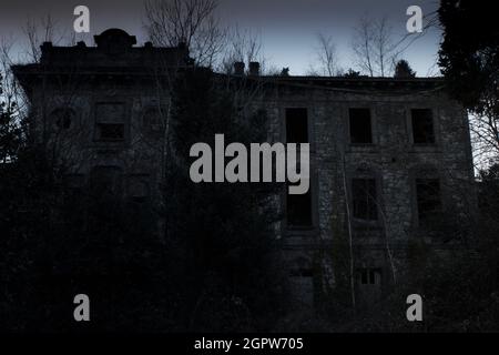 Casa abbandonata raffigurata al crepuscolo, con un aspetto spettrale adatto per cartoline per Halloween Foto Stock