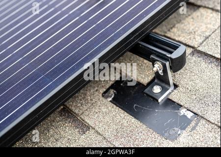 Binario, staffa e ancoraggio a un pannello solare installato su un tetto di ghiaia in asfalto Foto Stock