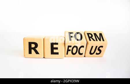 Simbolo di rifocalizzazione e riforma. L'uomo d'affari girò i cubi e cambiò la parola 'focus' in 'reform'. Bella tavola bianca, sfondo bianco. Business refo Foto Stock