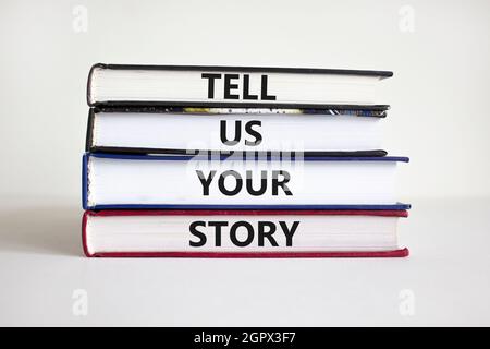 Raccontaci il tuo simbolo di storia. Libri con parole 'Dacci la tua storia'. Mano dell'uomo d'affari. Bellissimo sfondo bianco, spazio di copia. Affari, narrazione e. Foto Stock