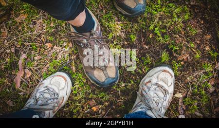 Scarpe da trekking o da passeggio di due donne viaggiatori in piedi nella foresta. Direttamente sopra la vista. Foto Stock