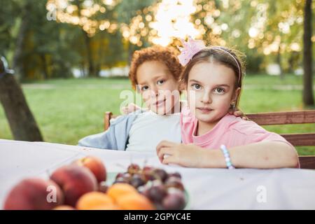 Ritratto di ragazzo e ragazza guardando la macchina fotografica mentre si siede al tavolo da picnic all'aperto, spazio copia Foto Stock