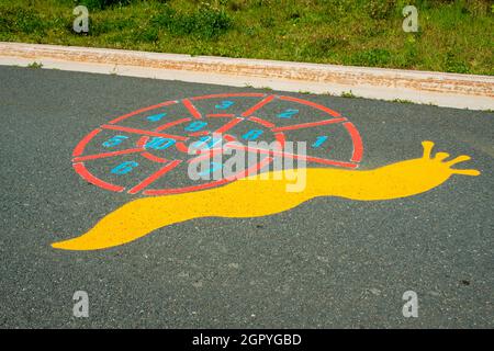 Un colorato gioco di divertimento per bambini all'aperto a forma di lumaca. Ci sono numeri o gioco di conteggio sulla parte shell della figura dipinta. Foto Stock