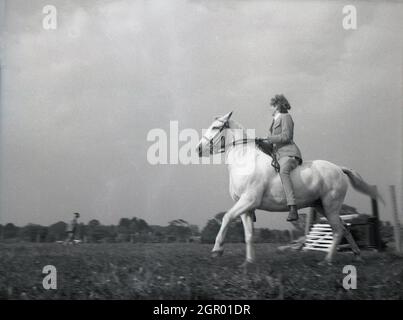 Anni '50, storico, fuori in un campo, una signora rider sul suo cavallo che partecipa a una competizione di eventi, Sussex, Inghilterra, Regno Unito. Foto Stock