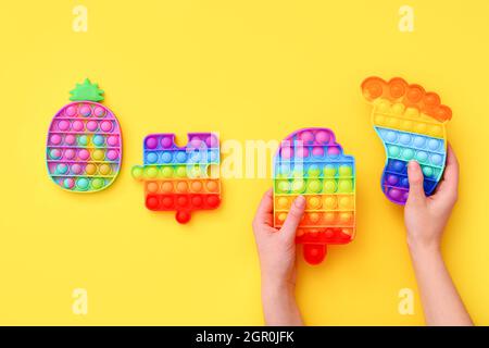 Pop a spinta colorato Bubble sensoriale Fidget Giocattoli di forme diverse su piano di boccale giallo Foto Stock