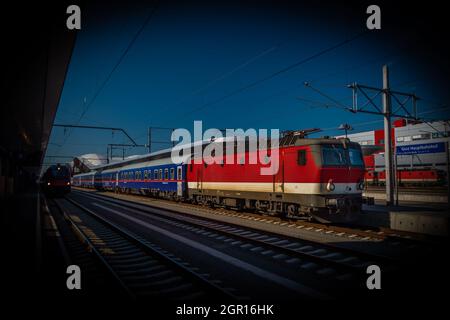 Treno passeggeri elettrico rosso alla stazione di Graz in estate soleggiata fresca mattina Foto Stock