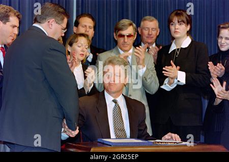 Washington, DC, Stati Uniti. 12 marzo 1996. Il presidente degli Stati Uniti Bill Clinton scrolla le mani con il Rep. Robert Menendez, (D-NJ), a sinistra, dopo la firma del disegno di legge Helms-Burton per inasprire l'embargo cubano al vecchio edificio dell'ufficio esecutivo della Casa Bianca 12 marzo 1996 a Washington, D.C. che circonda il presidente sono membri della famiglia dei Fratelli per i piloti di salvataggio che sono stati uccisi quando i loro aerei sono stati abbattuti da aerei da caccia cubani. Foto Stock