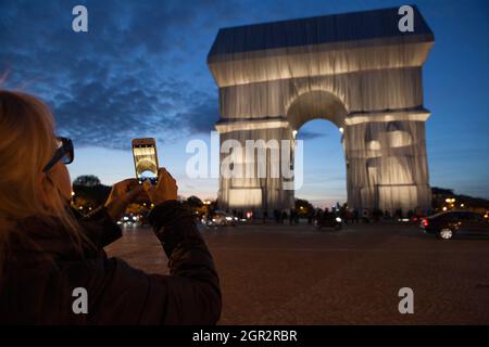 Parigi, Francia, 30 settembre 2021: L'Arco di Trionfo di Parigi, avvolto in tessuto d'argento come progettato dagli artisti Christo e Jeanne-Claude, e che attrae un flusso costante di turisti. Questo fine settimana, la Place Charles de Gaulle che circonda l'arco sarà chiusa al traffico, consentendo visite più sicure rispetto a coloro che hanno catturato alcuni colpi dal centro dei viali che irradiano dalla rotonda. L'installazione artistica sarà smantellata da lunedì 4 ottobre per consentire le celebrazioni del giorno dell'armistizio. Anna Watson/Alamy Live News Foto Stock