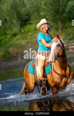 Ragazza mucca a cavallo attraverso il fiume Foto Stock