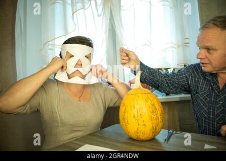 Facendo Jack o'Lantern a casa. La zucca è pronta per affettare. La donna è felice con il loro lavoro e ridere e scherzare. Foto Stock