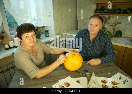 Facendo Jack o'Lantern a casa. Il processo di creazione di un modello di tema Jack o'Lantern. Un uomo e una donna stanno preparando una zucca per la scultura. Foto Stock