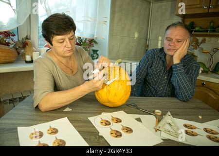 Facendo Jack o'Lantern a casa. Il processo di creazione di un modello di tema Jack o'Lantern. Un uomo e una donna stanno preparando una zucca per la scultura. Foto Stock