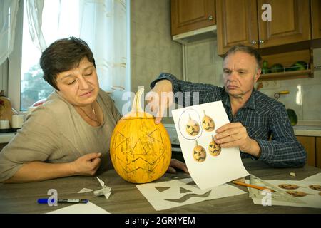 Facendo Jack o'Lantern a casa. Il processo di creazione di un modello di tema Jack o'Lantern. Un uomo e una donna stanno preparando una zucca per la scultura. Foto Stock