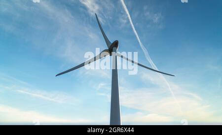 Colpo ad angolo basso di un generatore di vento sotto un cielo blu nuvoloso Foto Stock