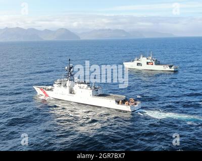 L'equipaggio Cutter Kimball della Guardia Costiera e un equipaggio della Marina reale Canadese, a bordo della nave militare Harry DeWolf, transitano l'uno accanto all'altro al largo della costa del Porto Olandese, il 23 settembre 2021. Gli equipaggi si scambiarono comunicazioni radio dopo aver reso onore lungo le ringhiere della nave. Foto della Guardia Costiera degli Stati Uniti. Foto Stock