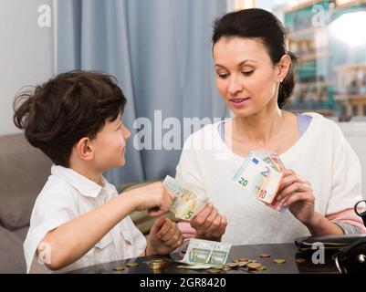 Donna che dà soldi a figlio Foto Stock