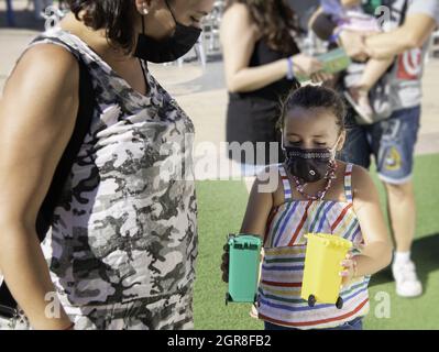 Ragazza caucasica con maschera che mostra una donna il verde e giallo bidoni spazzatura Foto Stock