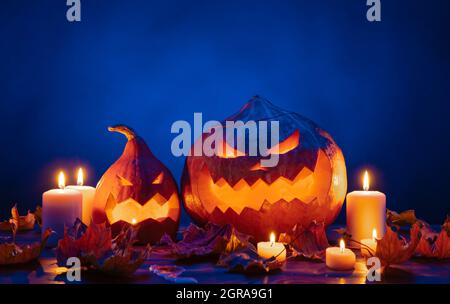 Due lanterne autunnali di zucca con facce intagliate per Halloween a lume di candela. Foto Stock