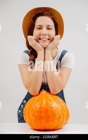 Agricoltore in tute sorridente riposante su una grande zucca biologica. Foto Stock
