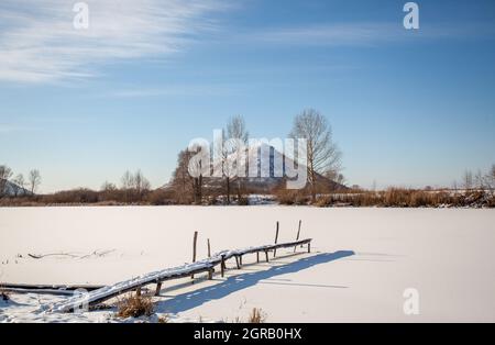 Passerella in legno coperta di neve su un laghetto ghiacciato Foto Stock