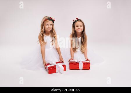 Due bambine in abiti bianchi con regali di Natale su sfondo bianco sorriso. Foto Stock