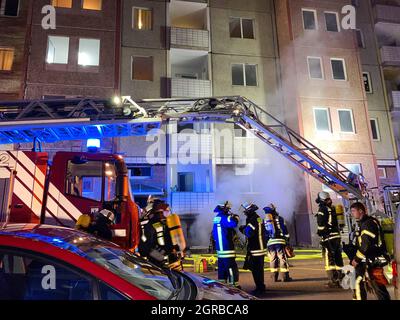 Magdeburg, Germania. 30 settembre 2021. I vigili del fuoco stanno estinguendo un incendio in un edificio di appartamenti a cinque piani nel quartiere Neue Neustadt, dove un incendio era scoppiato in un seminterrato. Molti residenti della casa si sono salvati saltando fuori dalle finestre. A causa del fumo pesante, la loro strada attraverso la scalinata è stata bloccata giovedì sera, come la polizia ha detto il venerdì mattina. Credit: Thomas Schulz/dpa/Alamy Live News Foto Stock