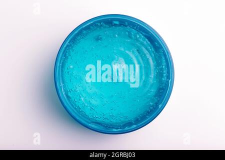 Gel cosmetico in vaso su sfondo bianco. Gel trasparente blu con consistenza e bolle isolano. Foto di alta qualità Foto Stock