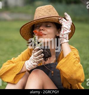 La donna tiene un fiore di petunia in una pentola di torba. Foto Stock