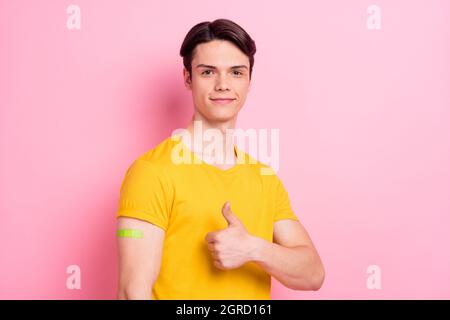 Foto di ragazzo affidabile sollevare pollice-up approva vaccinazione indossare t-shirt giallo isolato su sfondo rosa Foto Stock