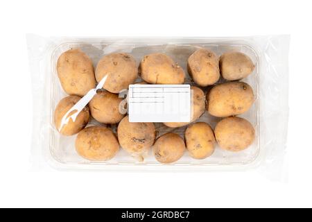 Patate appena raccolte in una confezione etichettata su sfondo bianco Foto Stock