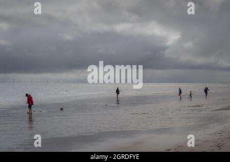 persone sulla spiaggia in tempo nuvoloso Foto Stock