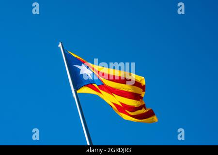 La bandiera Senyera estelada, quattro strisce rosse su un campo giallo e un triangolo blu con una stella sul lato sinistro, simbolo della rivendicazione di indipendenza di Foto Stock